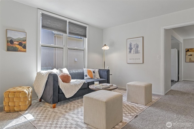 living area featuring light carpet and baseboards