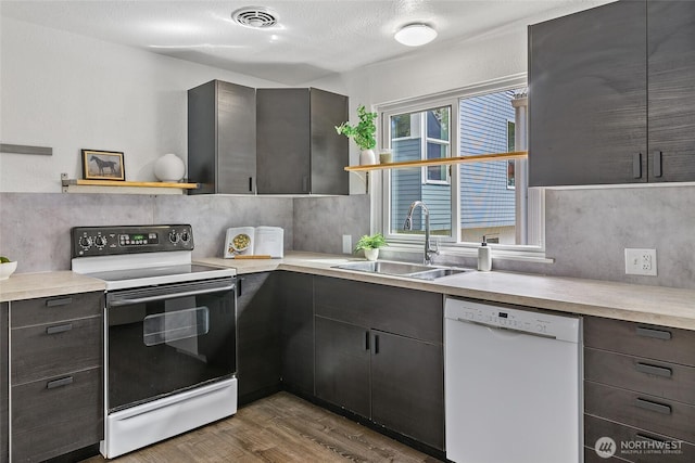 kitchen with white dishwasher, electric range oven, a sink, open shelves, and wood finished floors
