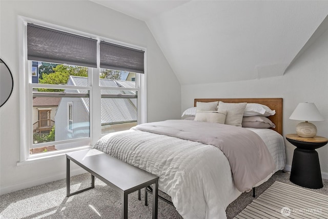 bedroom with vaulted ceiling, carpet flooring, and baseboards