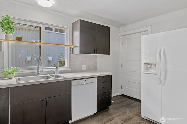 kitchen with white appliances, a sink, dark wood-style flooring, light countertops, and dark brown cabinetry
