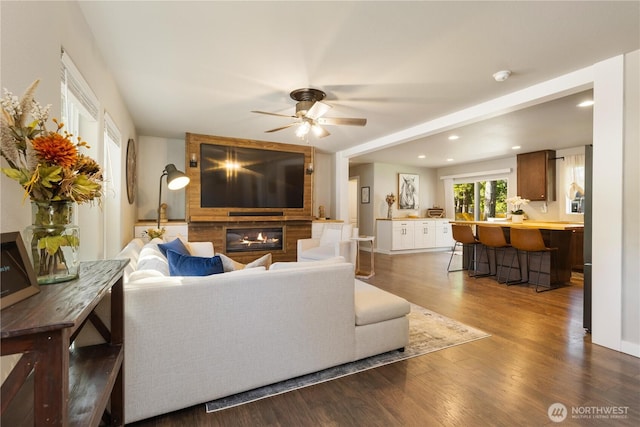 living room featuring a fireplace, dark wood-type flooring, ceiling fan, recessed lighting, and baseboards