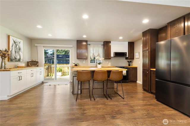 kitchen with appliances with stainless steel finishes, a kitchen breakfast bar, recessed lighting, light countertops, and a kitchen island