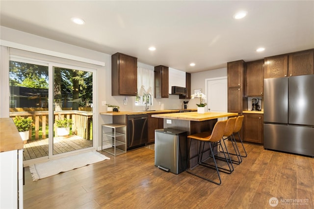 kitchen with stainless steel appliances, wooden counters, dark wood finished floors, extractor fan, and recessed lighting