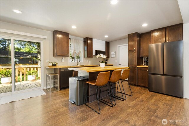 kitchen with stainless steel appliances, butcher block countertops, dark wood-style floors, recessed lighting, and a kitchen breakfast bar