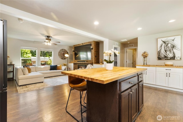 kitchen featuring wood counters, a breakfast bar, dark wood-type flooring, ceiling fan, and recessed lighting