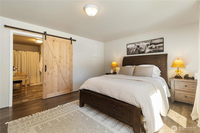 bedroom with a barn door and wood finished floors