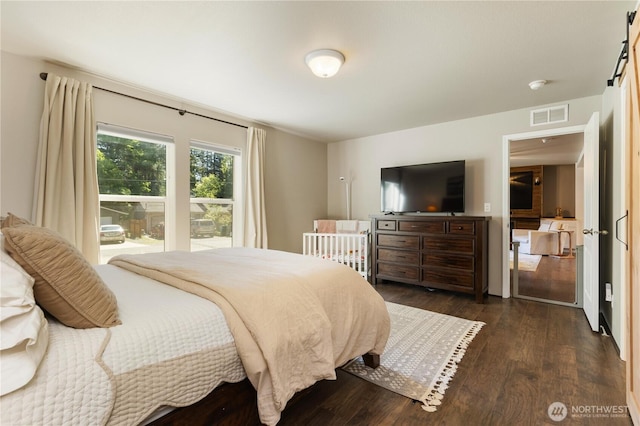bedroom with dark wood-type flooring and a barn door