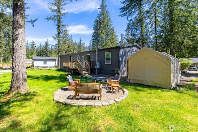 rear view of property with a wooden deck, a yard, a storage unit, an outdoor structure, and a patio area