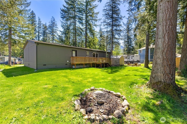 back of property with crawl space, a deck, a shed, and an outbuilding