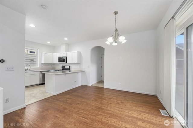 3516 Preston St NE, Lacey, WA 98516 - kitchen featuring appliances with stainless steel finishes, arched walkways, light wood-style floors, a peninsula, and light countertops