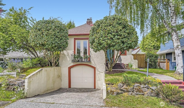 2523 Royal Ct E, Seattle, WA 98112 - view of front facade featuring french doors, stucco siding, a garage, and concrete driveway