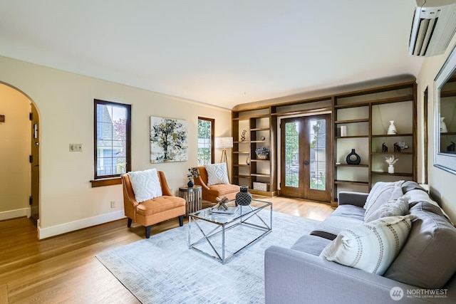 2523 Royal Ct E, Seattle, WA 98112 - living area with arched walkways, a wall mounted AC, light wood-style flooring, baseboards, and french doors