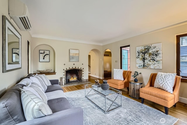 2523 Royal Ct E, Seattle, WA 98112 - living room featuring wood finished floors, a wall mounted air conditioner, arched walkways, and a warm lit fireplace