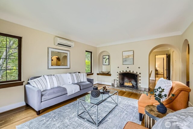 2523 Royal Ct E, Seattle, WA 98112 - living room with a wall mounted AC, wood finished floors, arched walkways, baseboards, and a fireplace