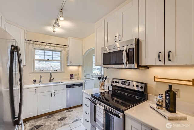 2523 Royal Ct E, Seattle, WA 98112 - kitchen featuring appliances with stainless steel finishes, a sink, light countertops, white cabinetry, and light tile patterned floors