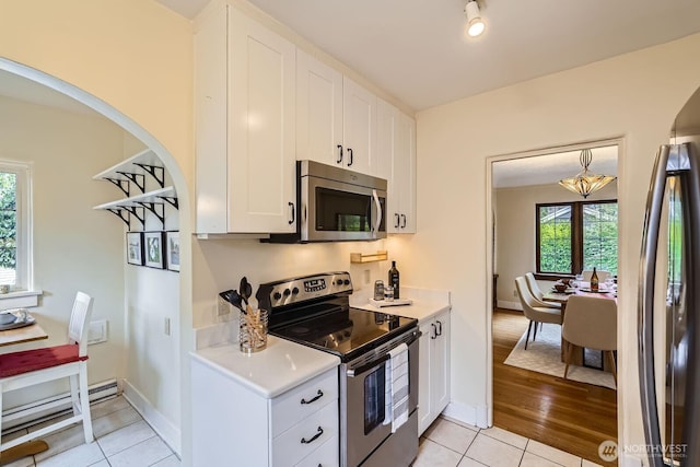 2523 Royal Ct E, Seattle, WA 98112 - kitchen with stainless steel appliances, light countertops, white cabinets, light tile patterned floors, and arched walkways