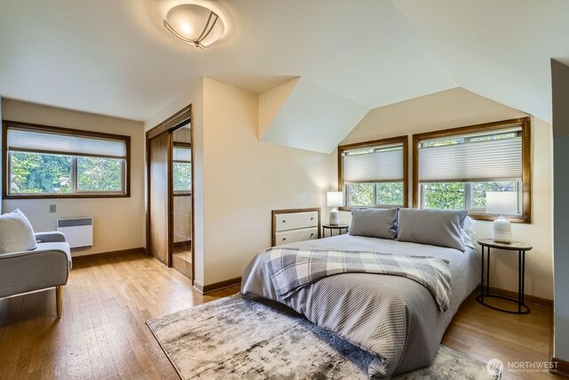2523 Royal Ct E, Seattle, WA 98112 - bedroom featuring radiator, multiple windows, light wood-style floors, baseboards, and lofted ceiling