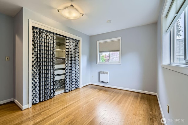 2523 Royal Ct E, Seattle, WA 98112 - unfurnished bedroom featuring wood-type flooring, baseboards, a closet, and heating unit
