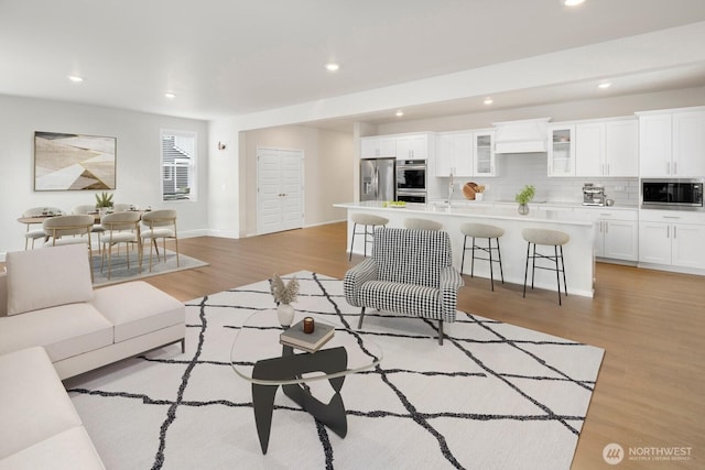 living area featuring baseboards, light wood-style floors, and recessed lighting
