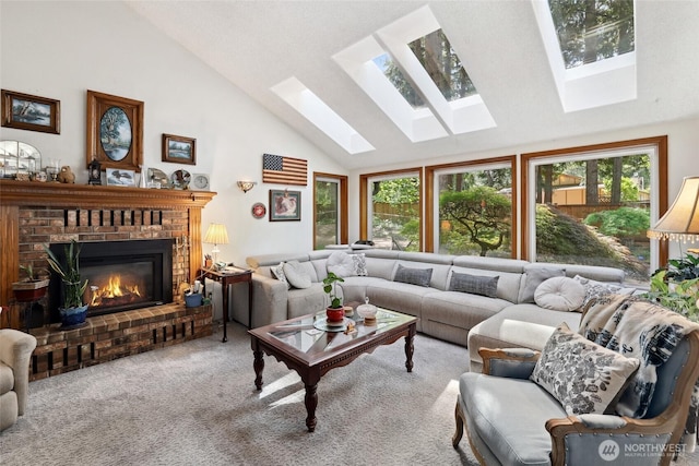 living room with a skylight, high vaulted ceiling, a brick fireplace, and carpet flooring