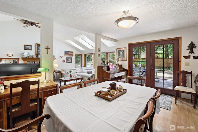 dining area with a skylight, french doors, plenty of natural light, a textured ceiling, and wood finished floors