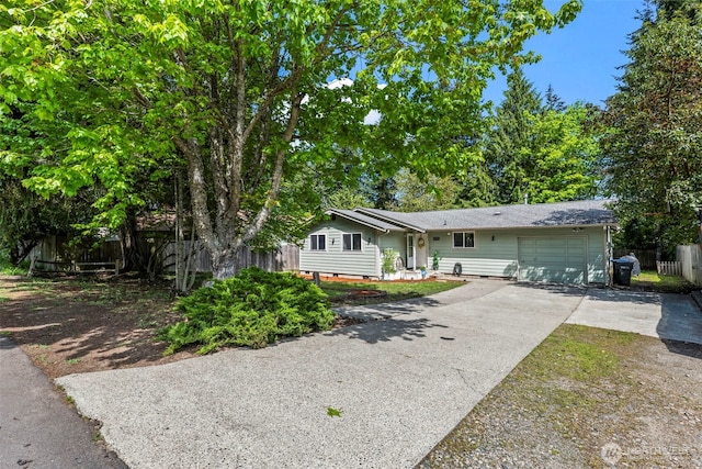 ranch-style house featuring fence, an attached garage, and driveway