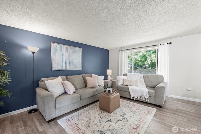 living area with baseboards, a textured ceiling, and wood finished floors