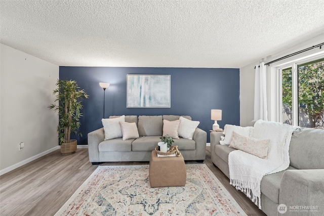 living room featuring a textured ceiling, wood finished floors, and baseboards