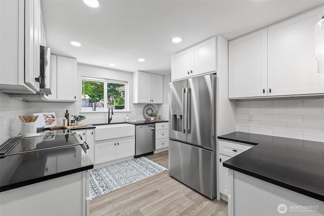 kitchen with dark countertops, stainless steel appliances, tasteful backsplash, and a sink