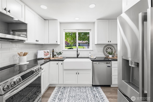 kitchen featuring stainless steel appliances, white cabinets, a sink, and tasteful backsplash
