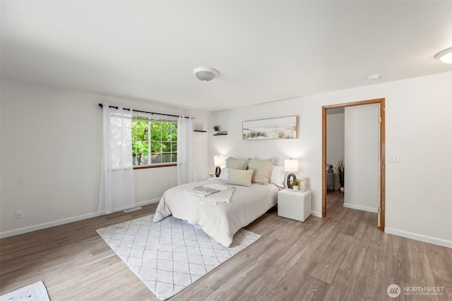 bedroom featuring baseboards, light wood finished floors, and visible vents