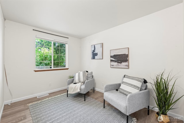 living area featuring baseboards, visible vents, and wood finished floors