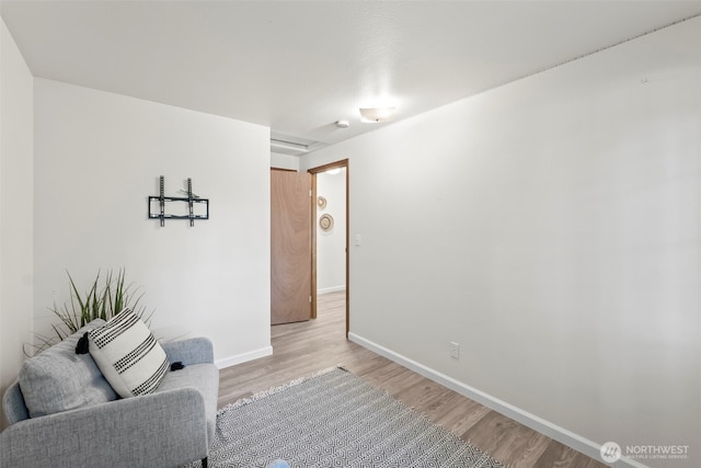 sitting room with baseboards and light wood-type flooring