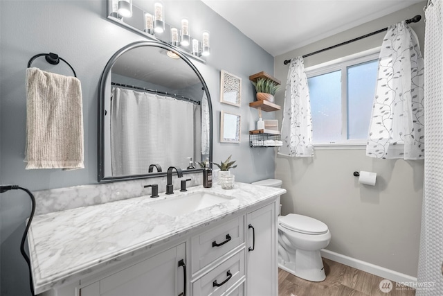 bathroom featuring vanity, toilet, baseboards, and wood finished floors
