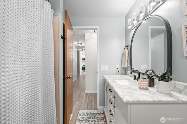 bathroom featuring baseboards, wood finished floors, vanity, and a shower with shower curtain