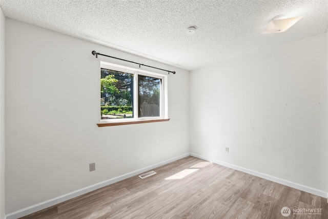 unfurnished room featuring a textured ceiling, visible vents, and wood finished floors