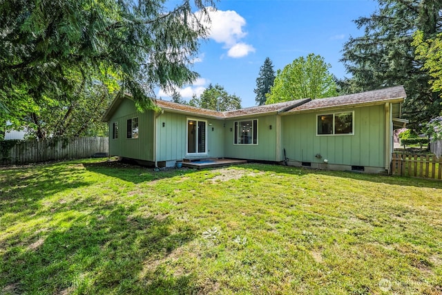rear view of house featuring fence and a lawn