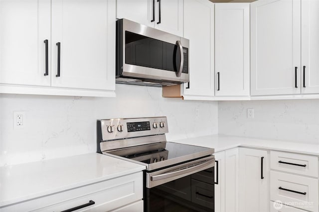 kitchen with appliances with stainless steel finishes, tasteful backsplash, white cabinetry, and light countertops