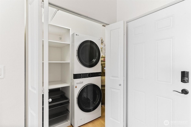 laundry area featuring stacked washer and clothes dryer and light wood-style flooring