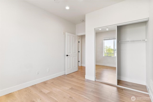 unfurnished bedroom featuring light wood finished floors, baseboards, a closet, and recessed lighting