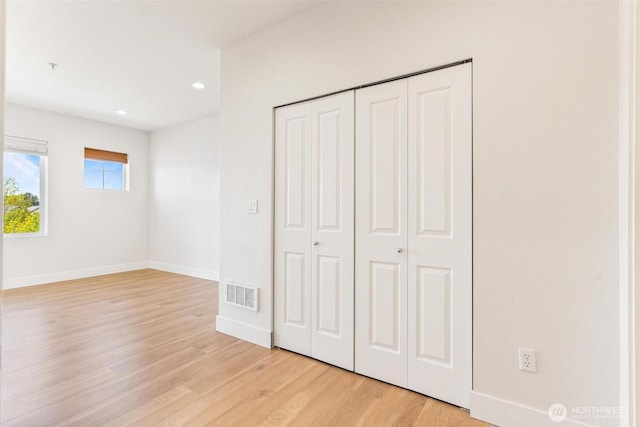unfurnished bedroom featuring light wood-style flooring, recessed lighting, a closet, and baseboards