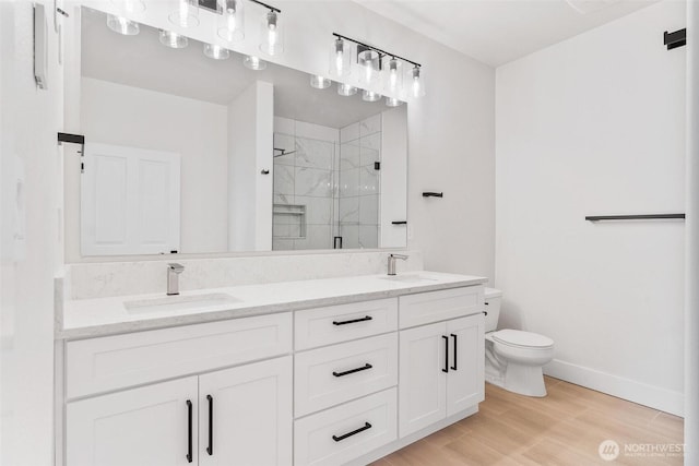 bathroom featuring toilet, a stall shower, wood finished floors, double vanity, and baseboards