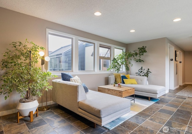 living room featuring baseboards, stone tile floors, recessed lighting, and a textured ceiling