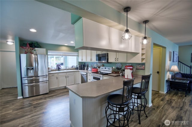 111 E Martin St, Elma, WA 98541 - kitchen with stainless steel appliances, a peninsula, dark wood-style floors, and white cabinets