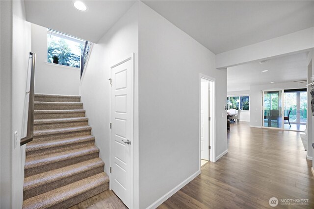 stairs featuring wood finished floors, recessed lighting, and baseboards