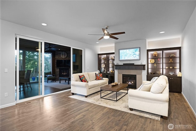 living area with a tile fireplace, ceiling fan, wood finished floors, healthy amount of natural light, and recessed lighting