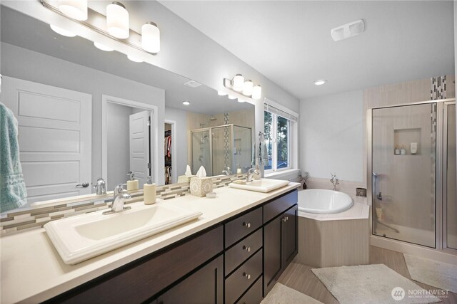 bathroom with a stall shower, a bath, double vanity, and a spacious closet
