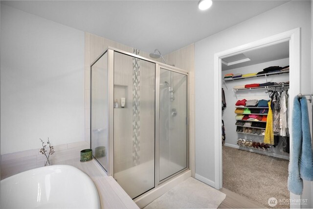 bathroom with a shower stall, a spacious closet, and a soaking tub