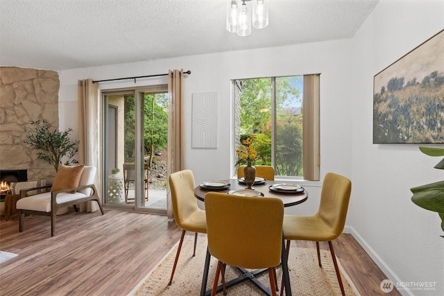 12515 NE 145th Pl Unit D121, Kirkland, WA 98034 - dining area featuring wood finished floors, a textured ceiling, a fireplace, and baseboards