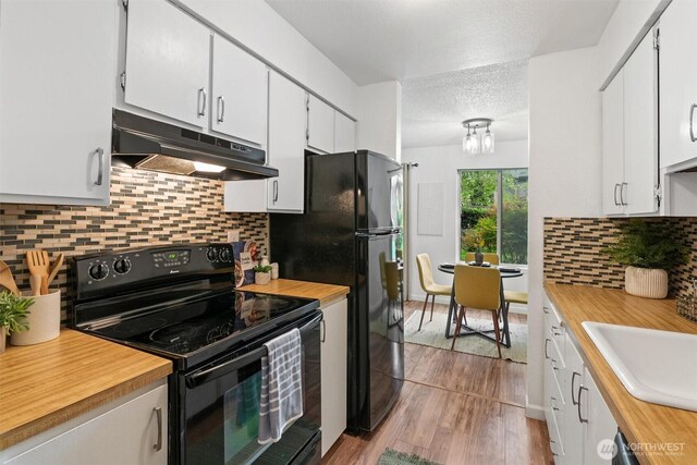 12515 NE 145th Pl Unit D121, Kirkland, WA 98034 - kitchen featuring black appliances, under cabinet range hood, wooden counters, white cabinetry, and a textured ceiling
